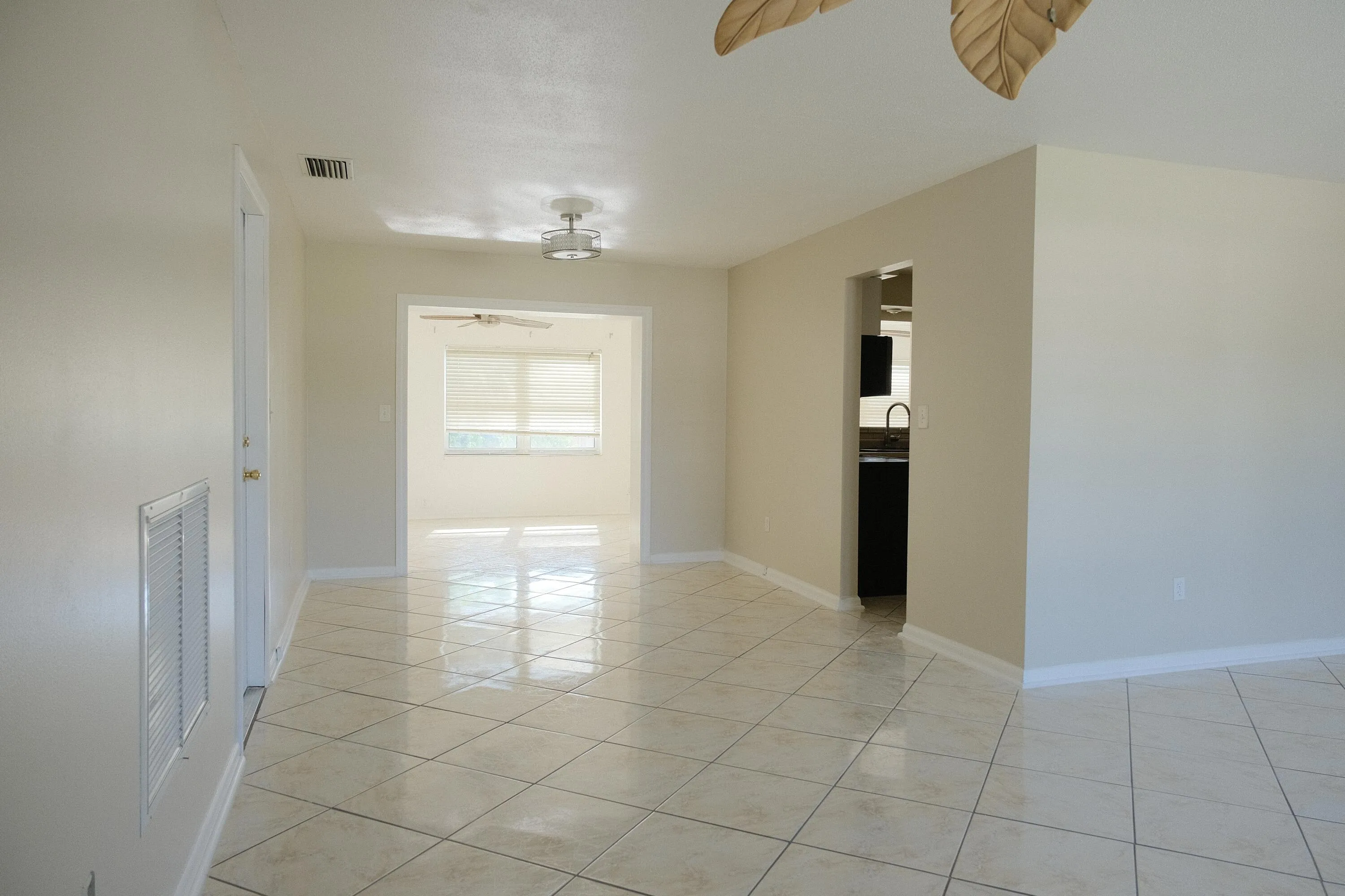 Spacious interior featuring tile flooring throughout, neutral paint, recessed lighting, and an open doorway to an additional room with a ceiling fan and large window