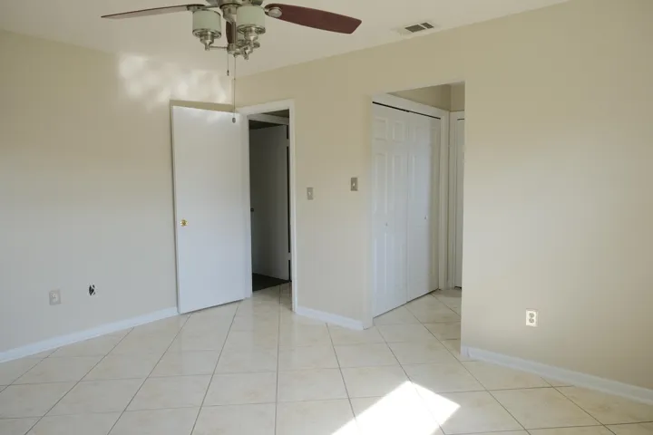 Spacious room featuring neutral painted walls, tile flooring, and white baseboards