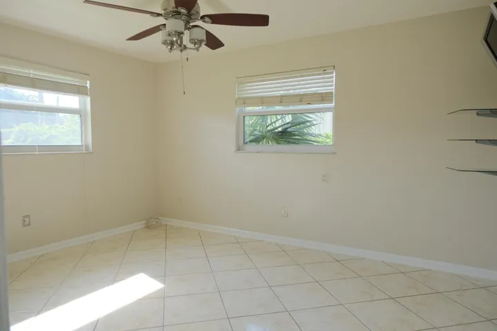 Bright room featuring neutral-toned tile flooring and a ceiling fan with integrated lighting