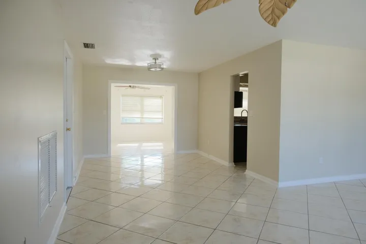 Spacious interior featuring tile flooring throughout, neutral paint, recessed lighting, and an open doorway to an additional room with a ceiling fan and large window