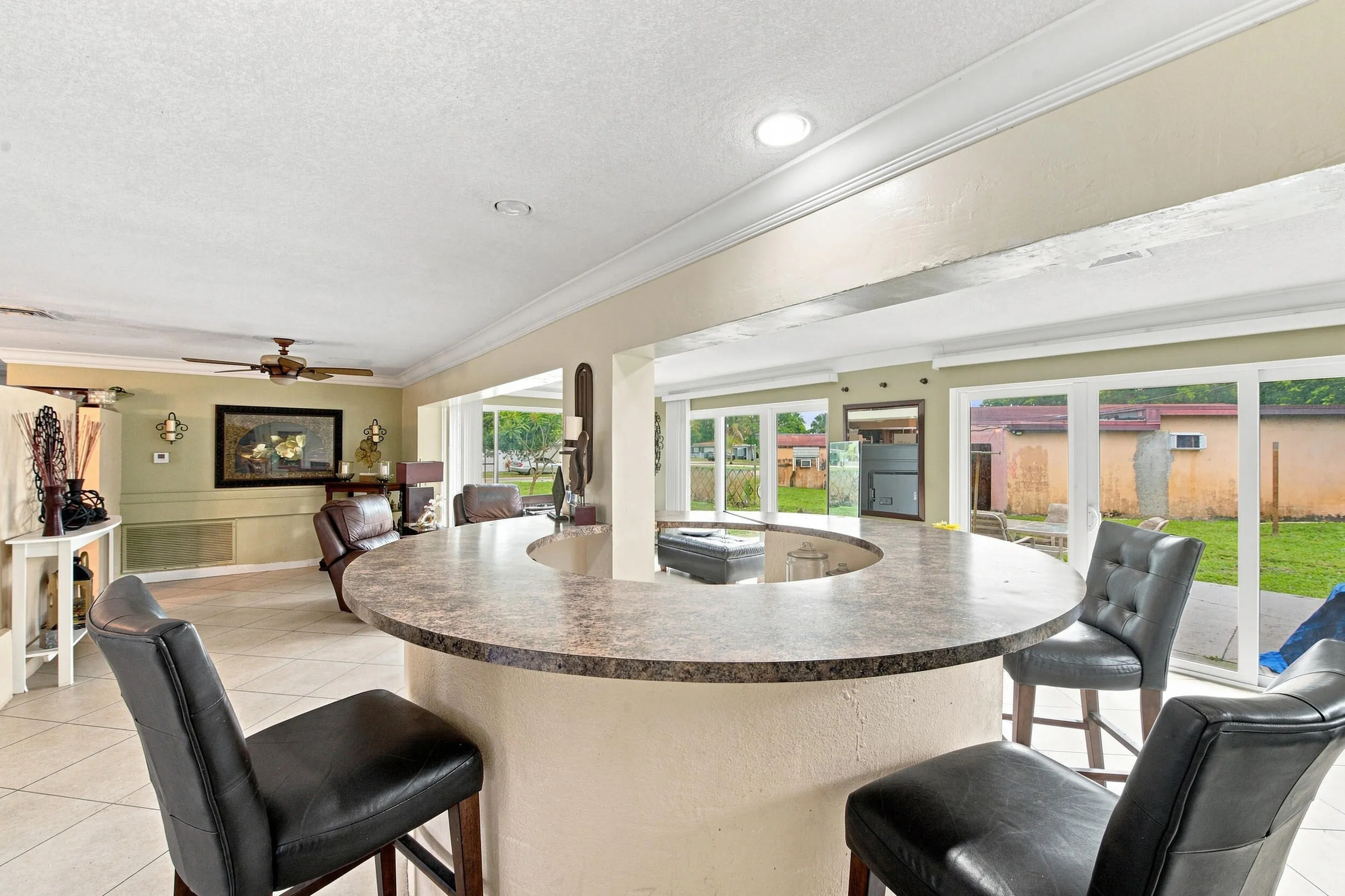 Circular countertop bar with a speckled finish, recessed lighting, and expansive sliding glass doors