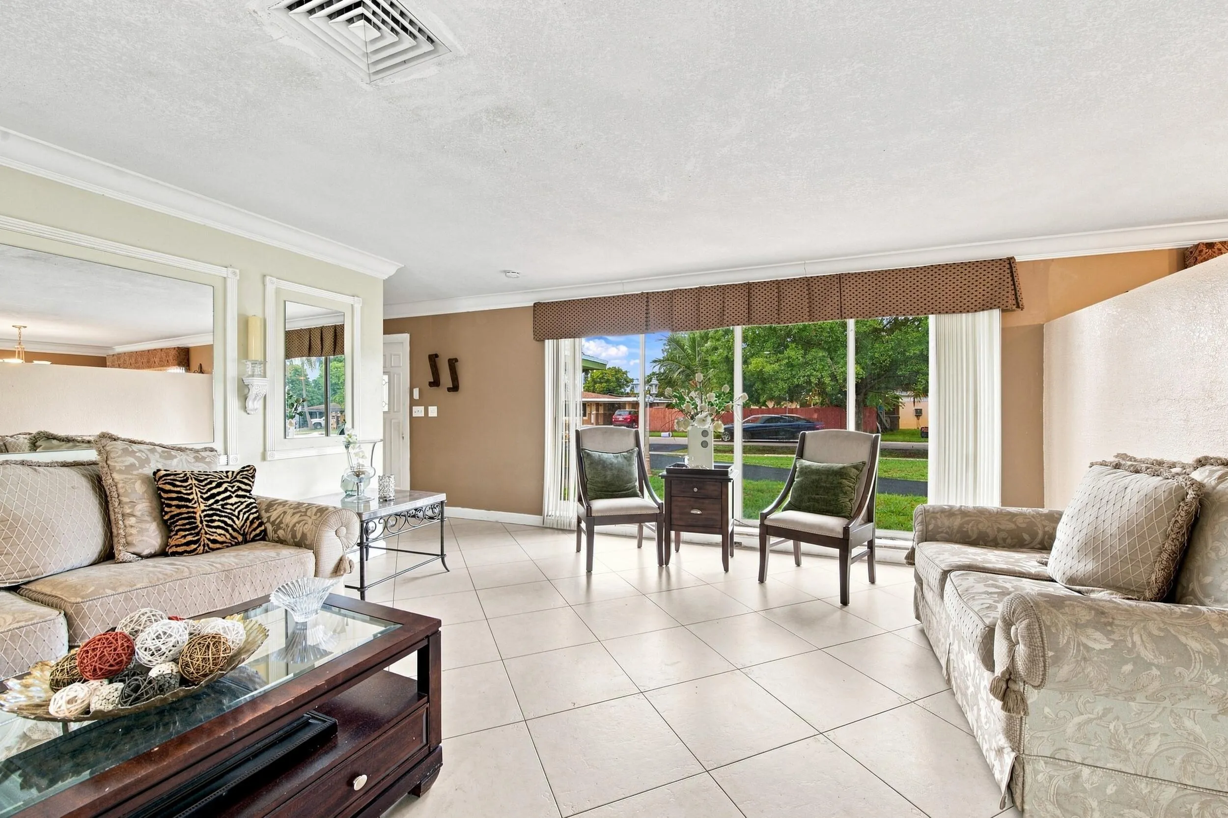 Spacious interior featuring light-toned tile flooring, crown molding, and large windows with transom detail