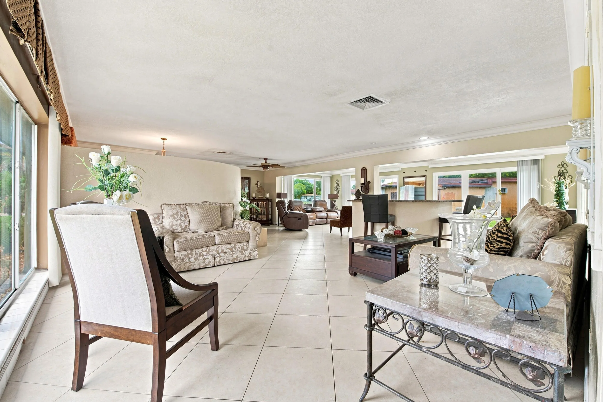Expansive interior living space featuring large format tile flooring, crown molding, and recessed lighting