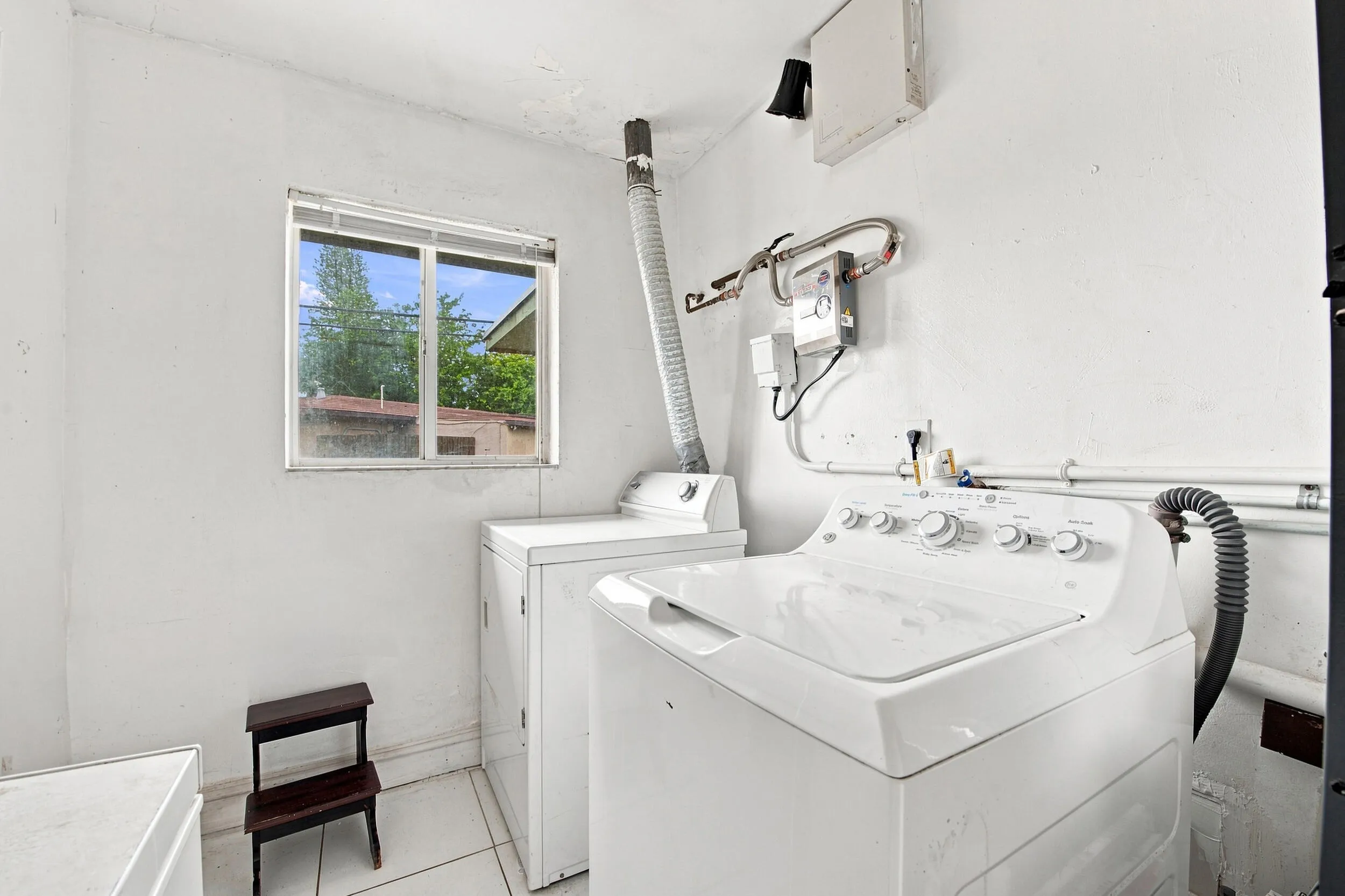 Dedicated laundry room with white tile flooring and a window providing natural light