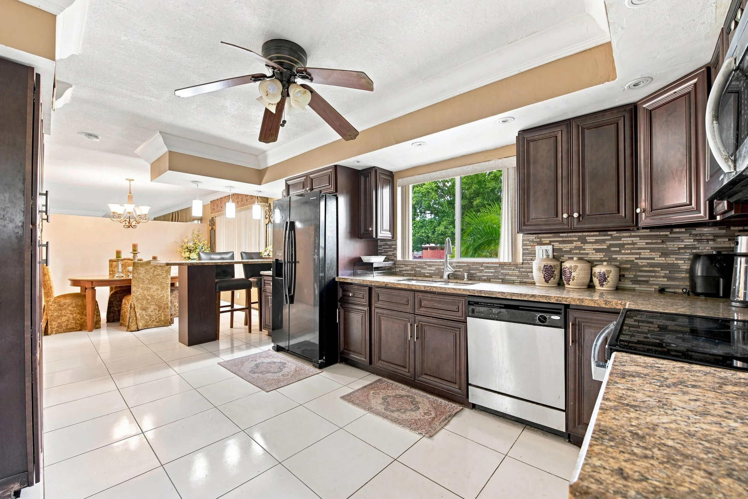 Kitchen featuring wood cabinetry, stainless steel appliances, a mosaic tile backsplash, and a breakfast bar
