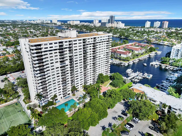 Multi-story high-rise residential building featuring private balconies, an outdoor swimming pool, and a tennis court