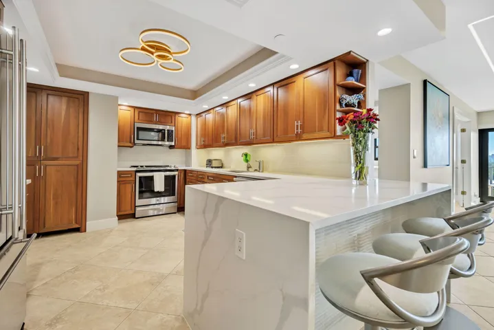 upgraded kitchen featuring quartz counter top with waterfall