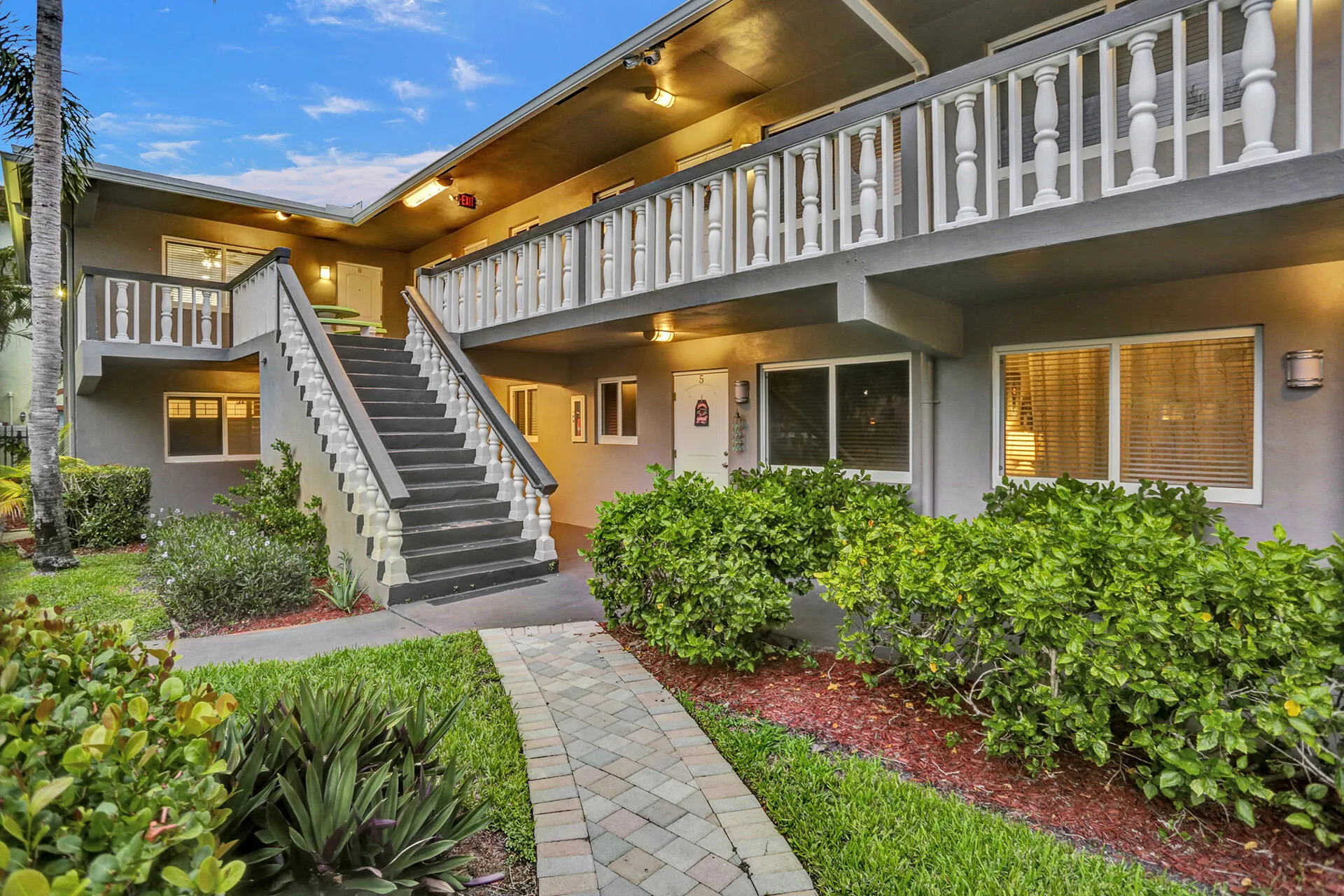 Multi-story exterior with a grand central staircase featuring white balusters and dark treads