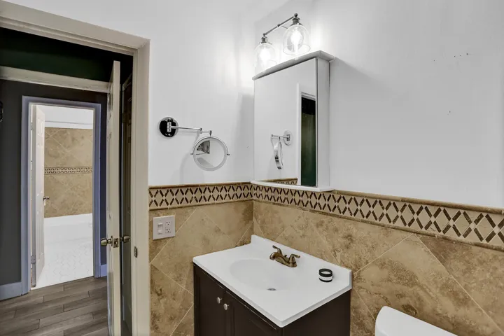 Bathroom vanity with a white countertop and integrated sink, bronze-finish faucet, and coordinating wall-mounted light fixture