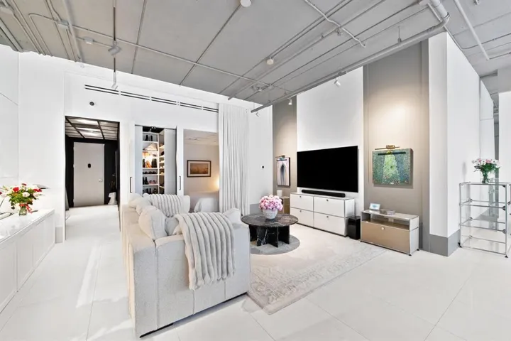 Open-concept living space featuring high ceilings with exposed conduit, track lighting, and light-toned tile flooring