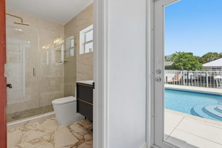 Bathroom featuring a glass-enclosed shower with rain shower head, a modern vanity with integrated sink, and stone-look tile flooring