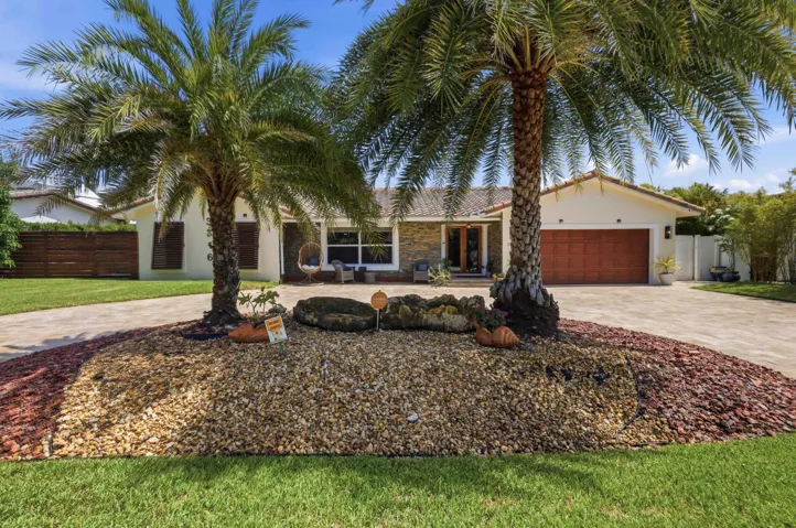 Front exterior featuring a circular driveway, mature palm trees, and a terracotta tile roof