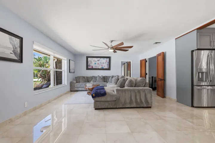Spacious interior featuring a contemporary ceiling fan, light-toned tile flooring, and large windows with outdoor scenery