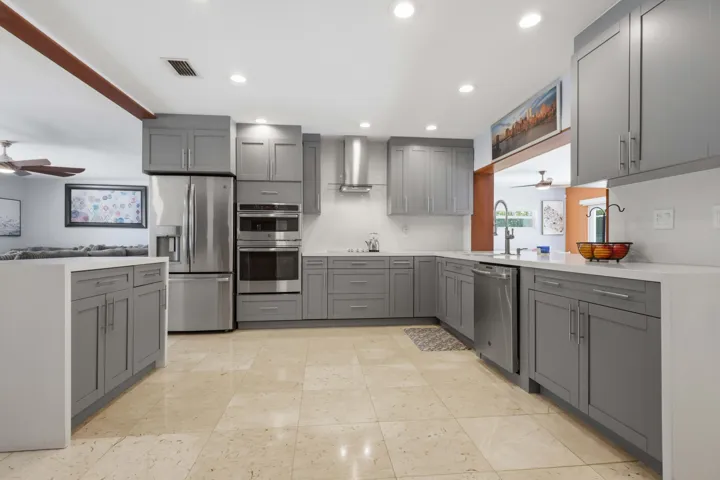 Modern kitchen featuring light gray shaker-style cabinetry, stainless steel appliances, recessed lighting, white countertops, and light-toned tile flooring