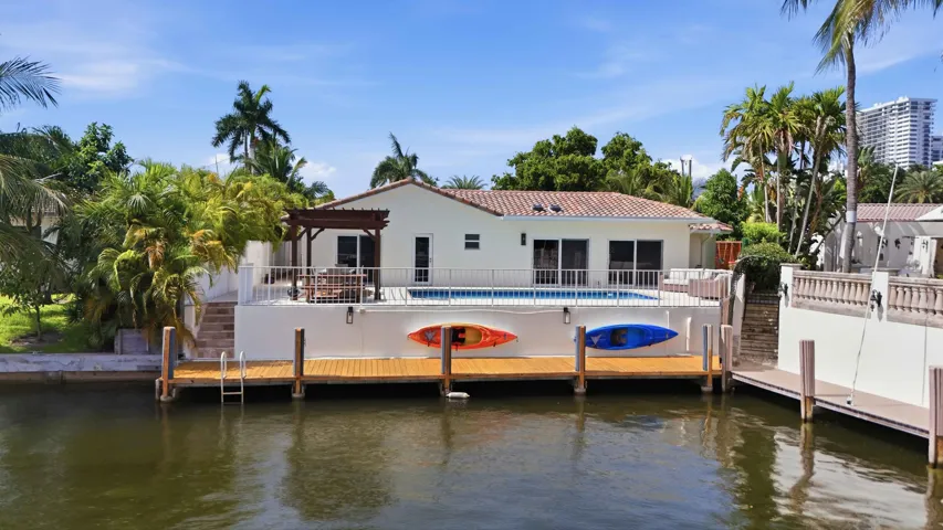 Waterfront property featuring a private dock with direct water access, a pool deck with a pergola, and a tiled roof residence