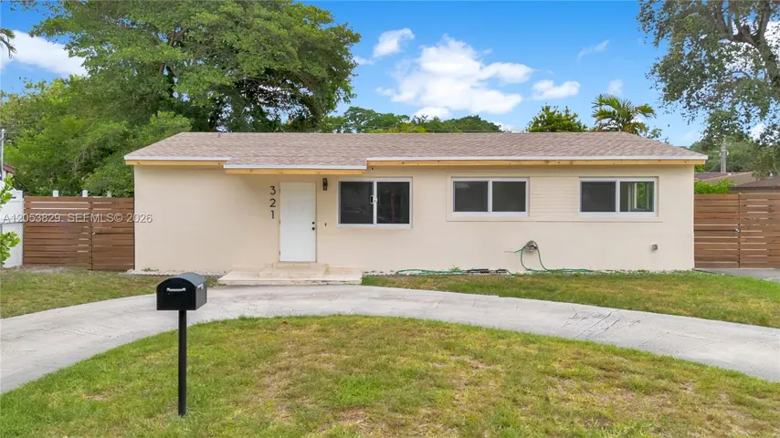 Front view showcasing the home's new roof, updated windows, modern wood privacy fencing, and spacious front yard.