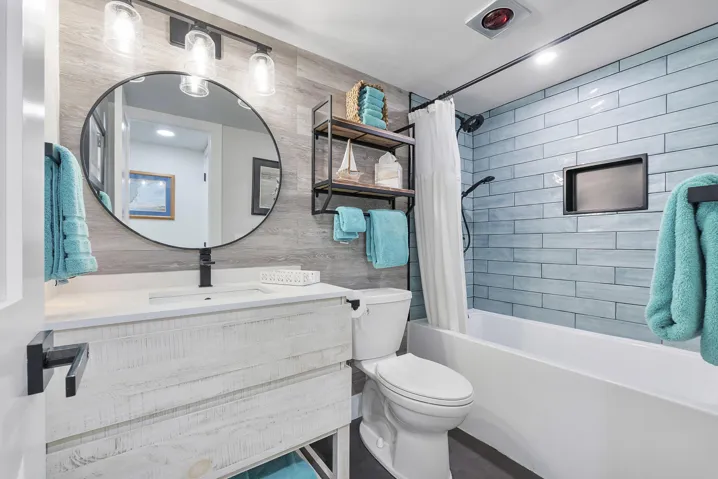 The coastal guest bathroom with soaking tub & modern white and turquoise finishes compliments the colors of the ocean,