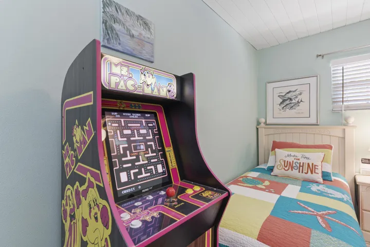 Guest bedroom features twin beds and a life size arcade Ms. Pac Man
