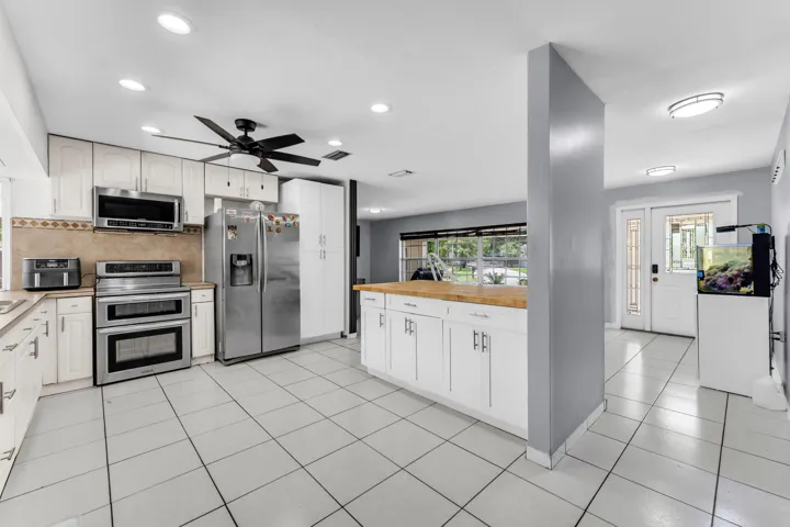 Kitchen featuring white cabinetry, stainless steel appliances, a wood-finish island countertop, and tile flooring