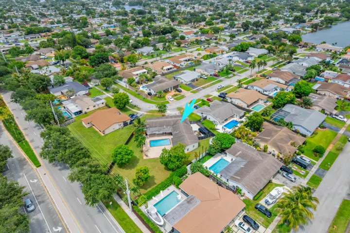 Residential property featuring a private swimming pool, mature landscaping, fenced yard, and an established neighborhood setting