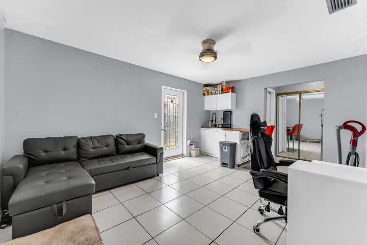Spacious room featuring white tile flooring, light gray walls, and a ceiling-mounted light fixture