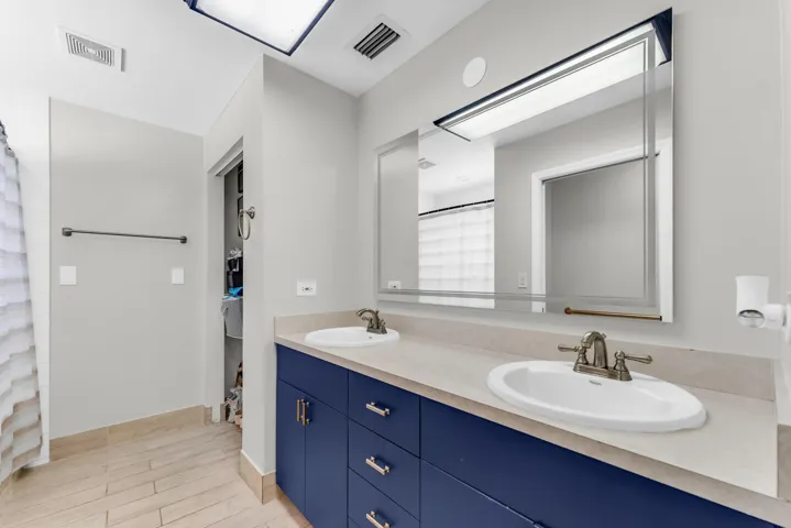 Double vanity with blue cabinetry, dual undermount sinks, and light-toned countertops