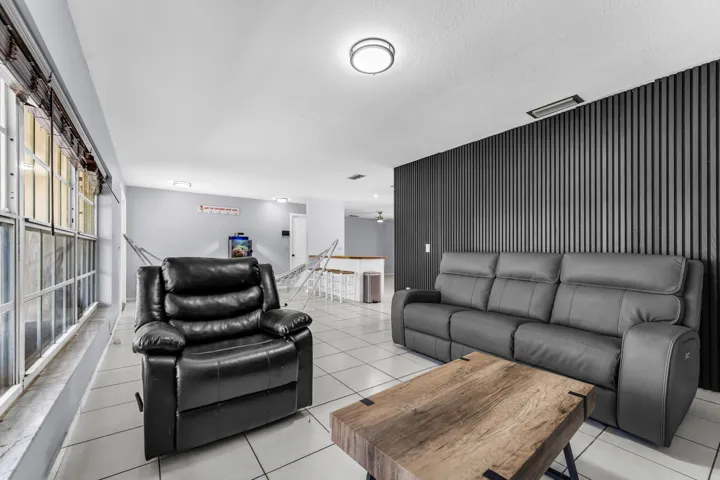 Living area featuring a textured accent wall, tile flooring, and multiple windows