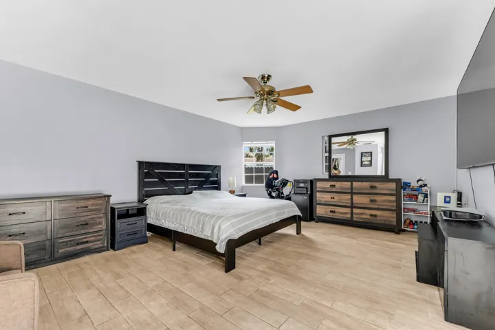 Spacious room featuring wood-finish flooring, a ceiling fan with integrated lighting, and light-toned walls