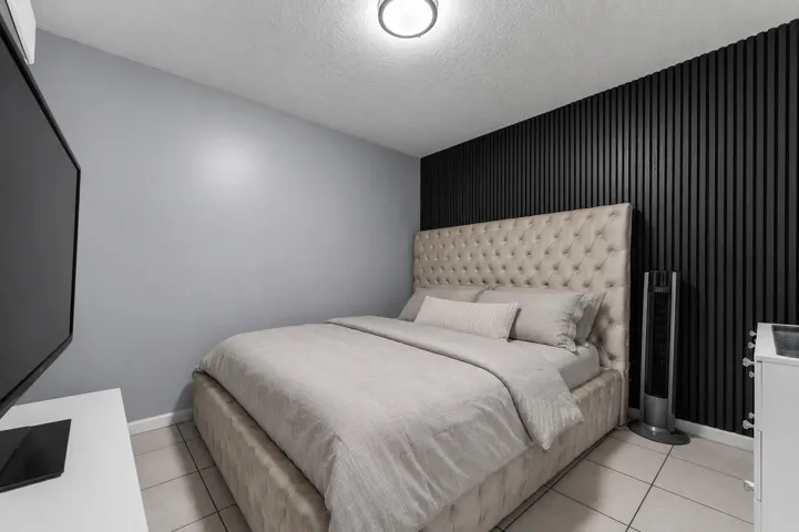 Room featuring a textured accent wall, light gray painted walls, and white tile flooring
