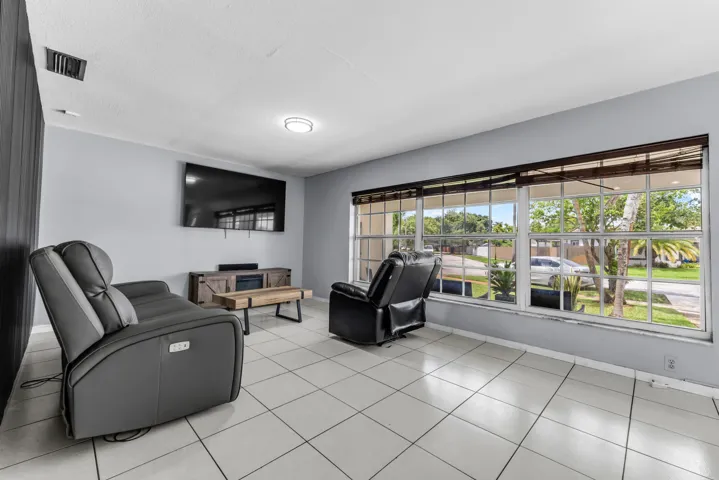 Living area featuring large multi-pane windows, light gray wall paint, and white tile flooring