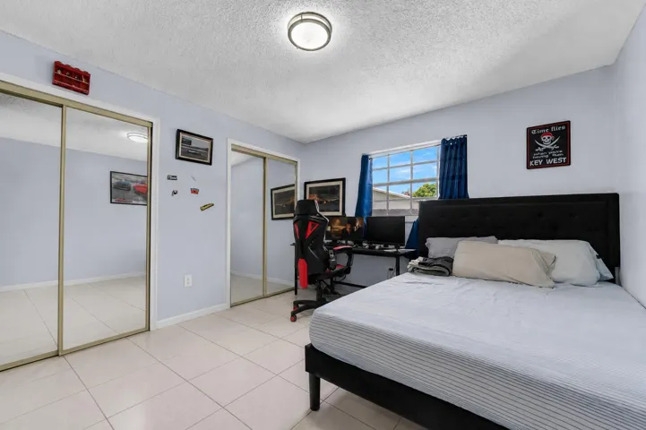 Bedroom featuring light blue walls, white tile flooring, a window with exterior views
