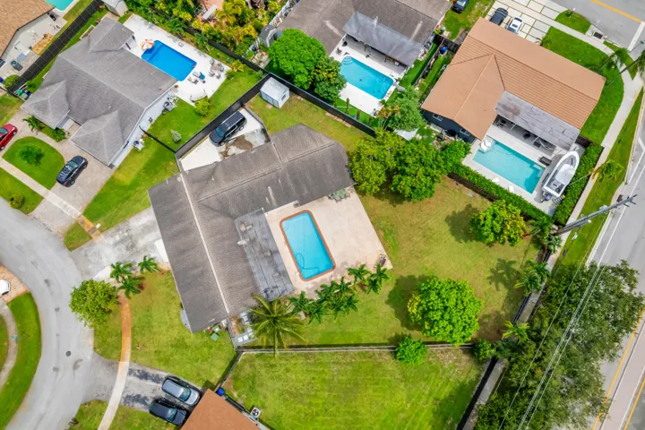 Aerial perspective of a property featuring a central swimming pool and surrounding green lawn