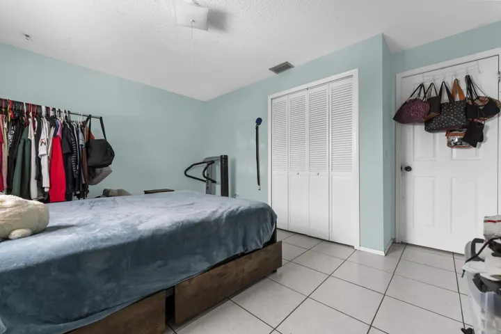 Bedroom featuring light blue walls, white ceiling, and square tile flooring