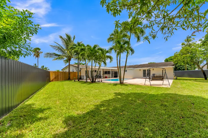 Expansive green lawn with a dark privacy fence along the perimeter