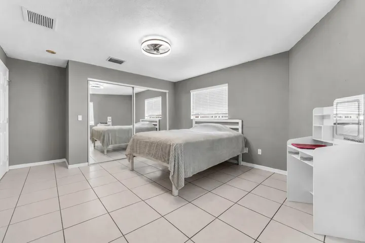 Spacious room featuring neutral gray walls, large format tile flooring, and a sliding mirrored closet door