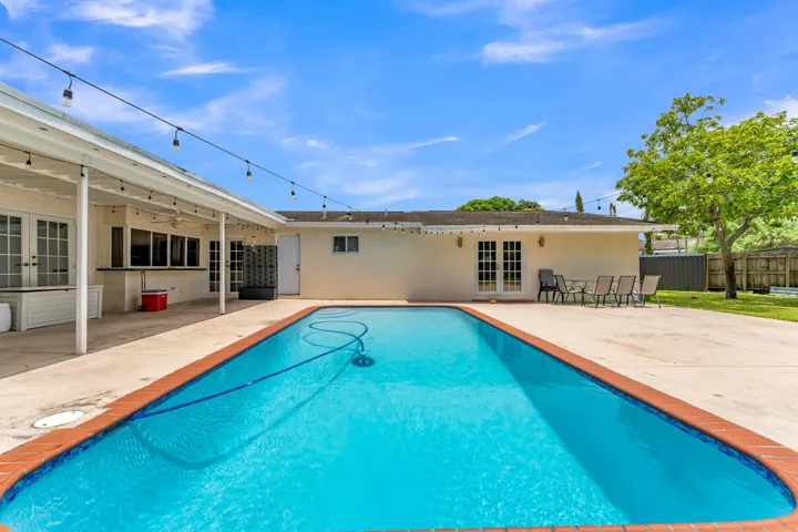 Outdoor swimming pool with a brick coping, surrounded by a concrete patio