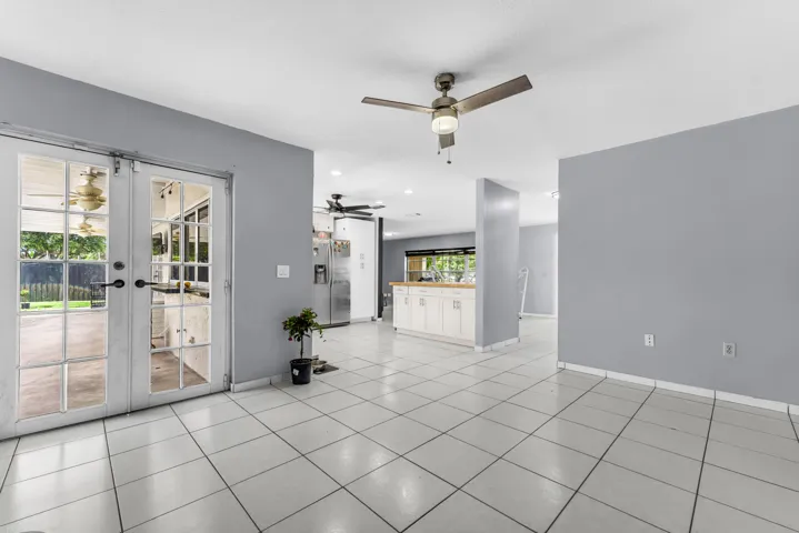 Spacious interior featuring light gray wall paint, white square tile flooring, and a ceiling fan
