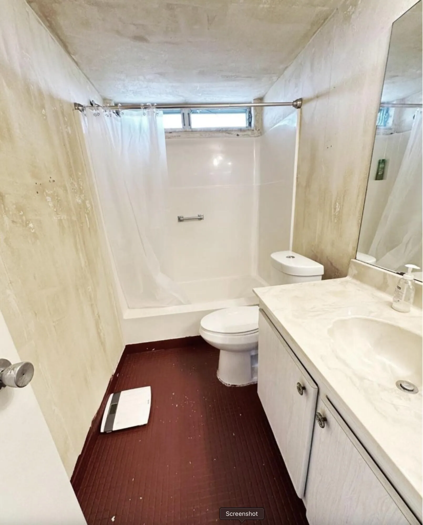Bathroom featuring a white vanity with integrated sink, a built-in shower/tub combination, and a horizontal window