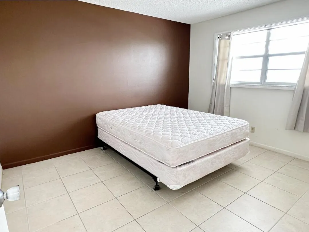Room featuring ceramic tile flooring, a window with horizontal panes, and a brown accent wall