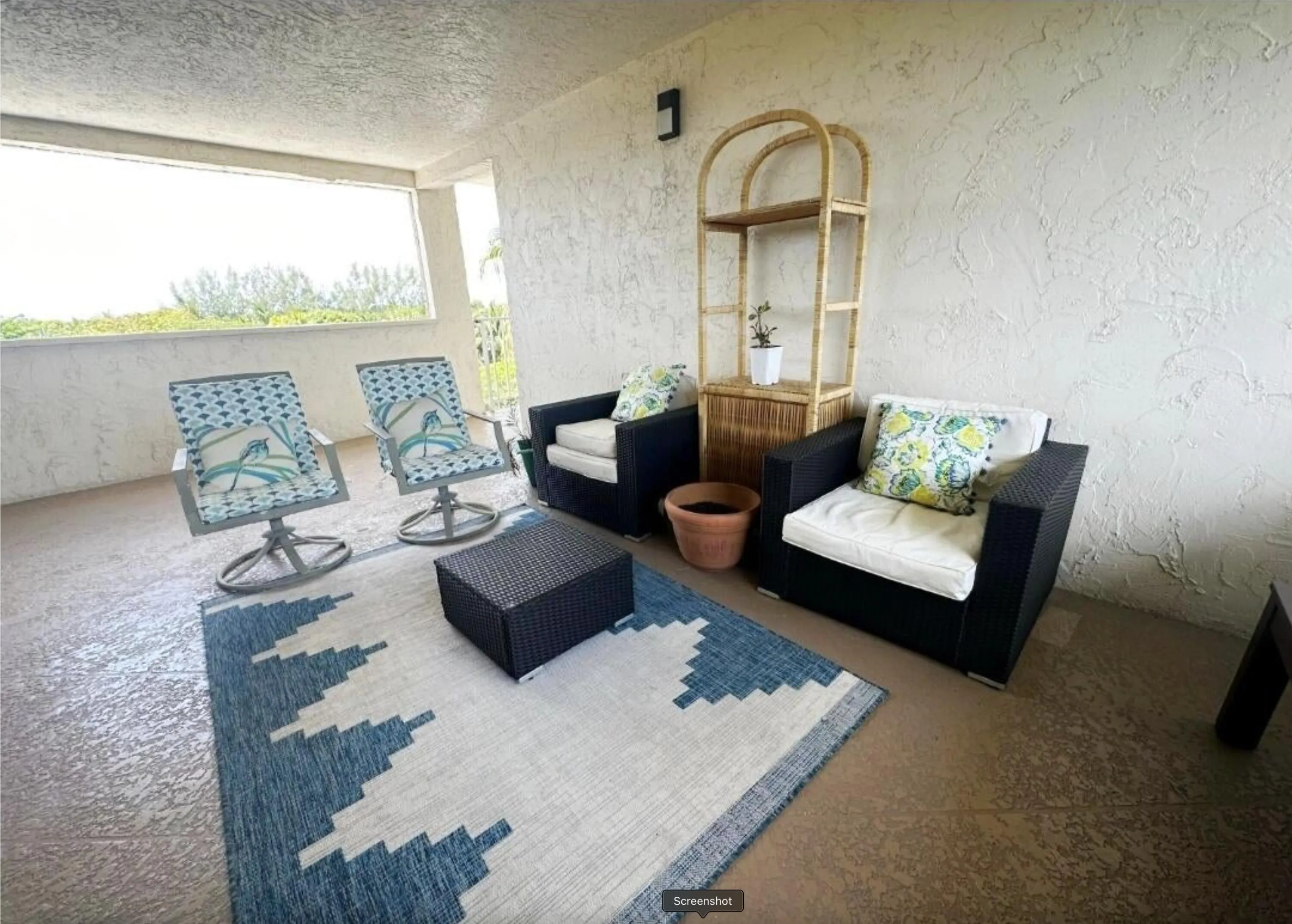 Virtually Staged Covered outdoor balcony featuring a textured wall finish and a partial privacy wall
