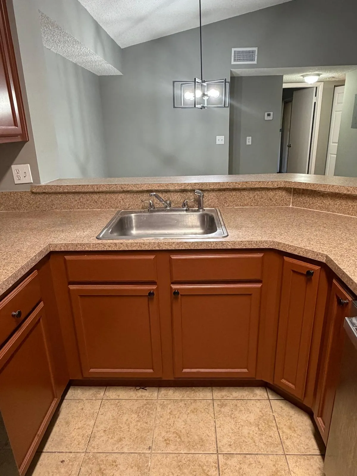 Kitchen featuring a stainless steel sink, speckled countertops, and wood-finish cabinetry