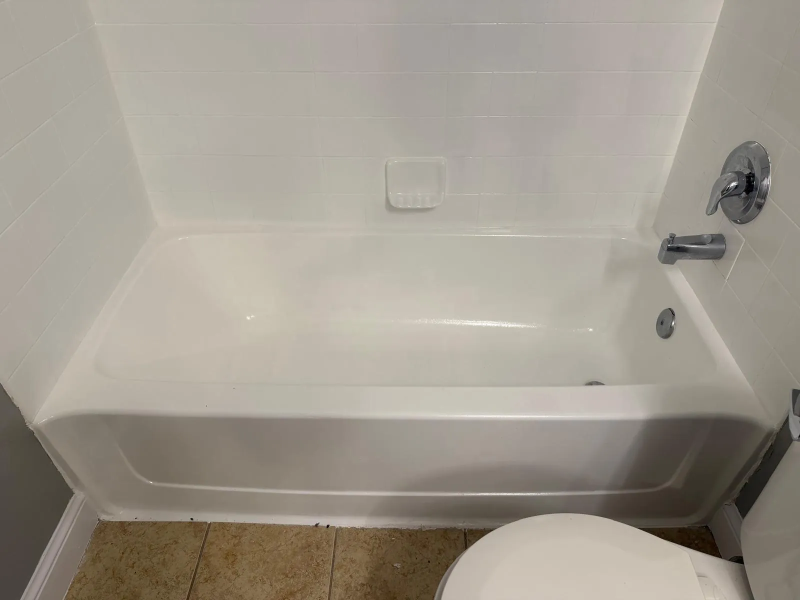 White bathtub with tile surround and chrome fixtures