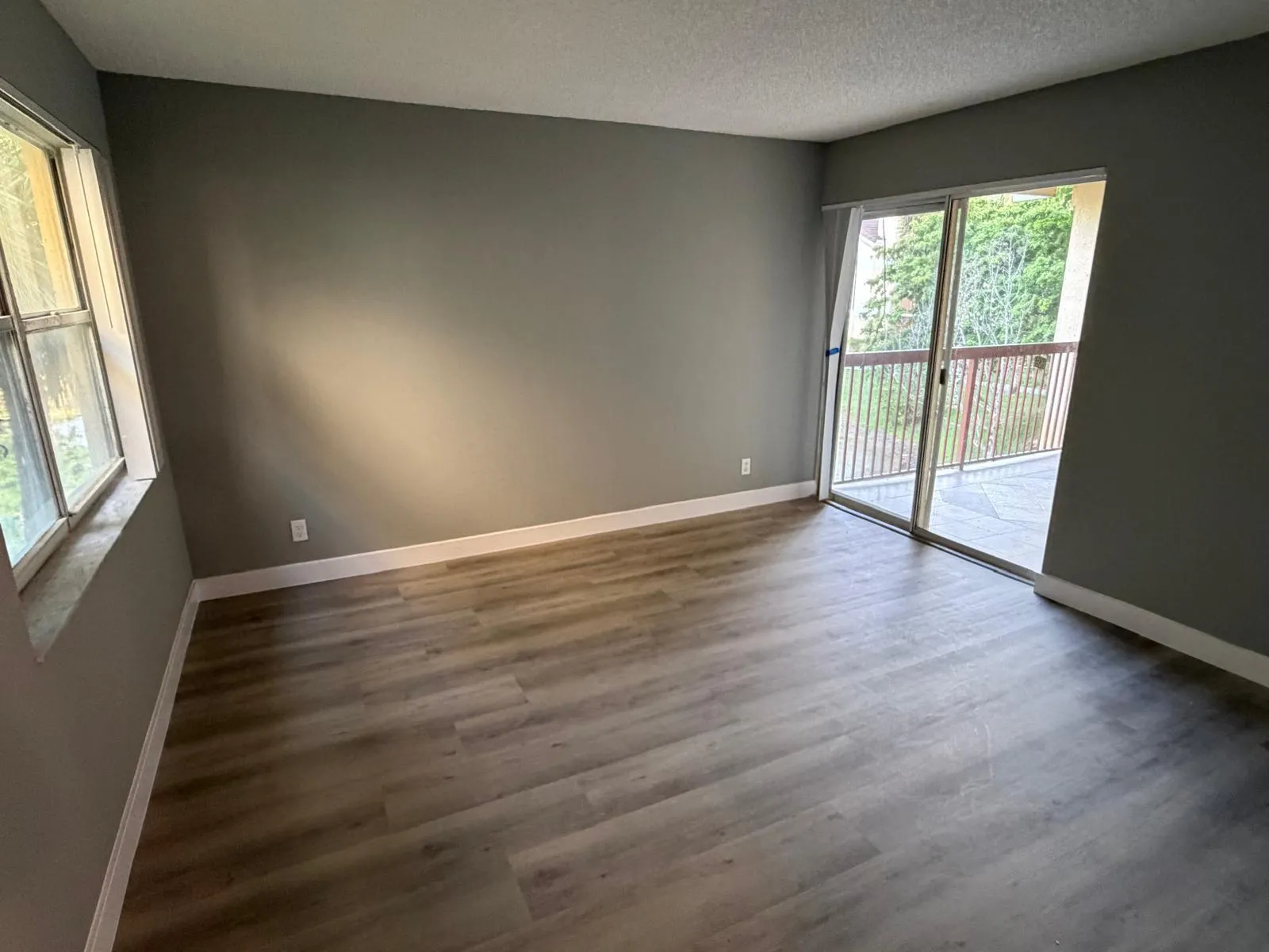 Room featuring wood-finish flooring, neutral wall paint, and white baseboards