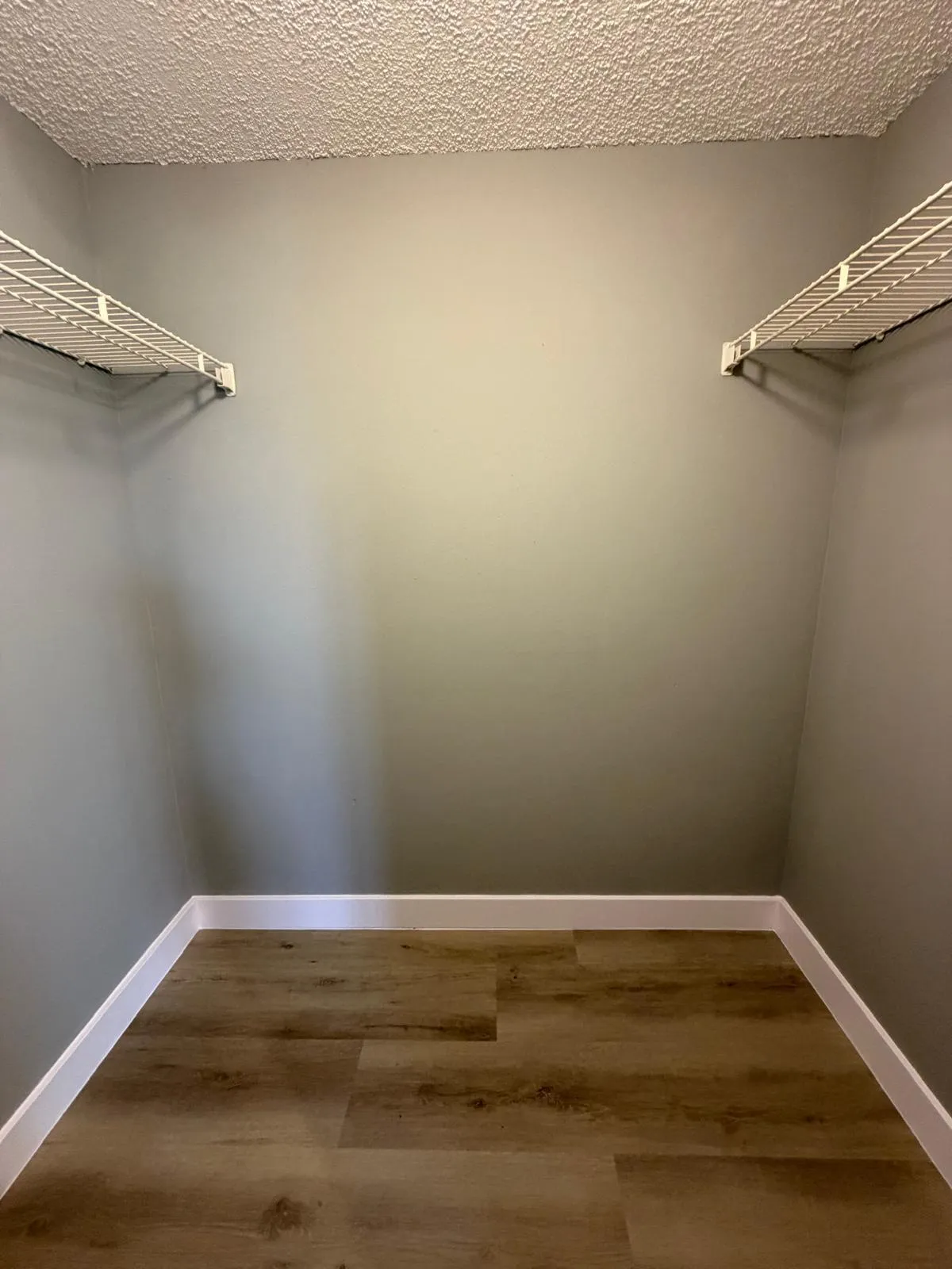 Compact storage space featuring wood-finish flooring, white baseboards, and neutral wall tones