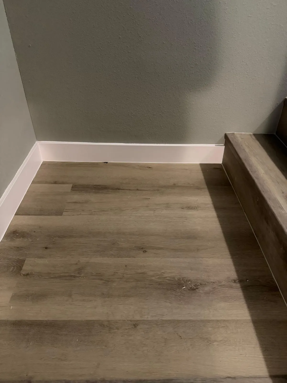 Wood-finish flooring with crisp white baseboards and a neutral wall color