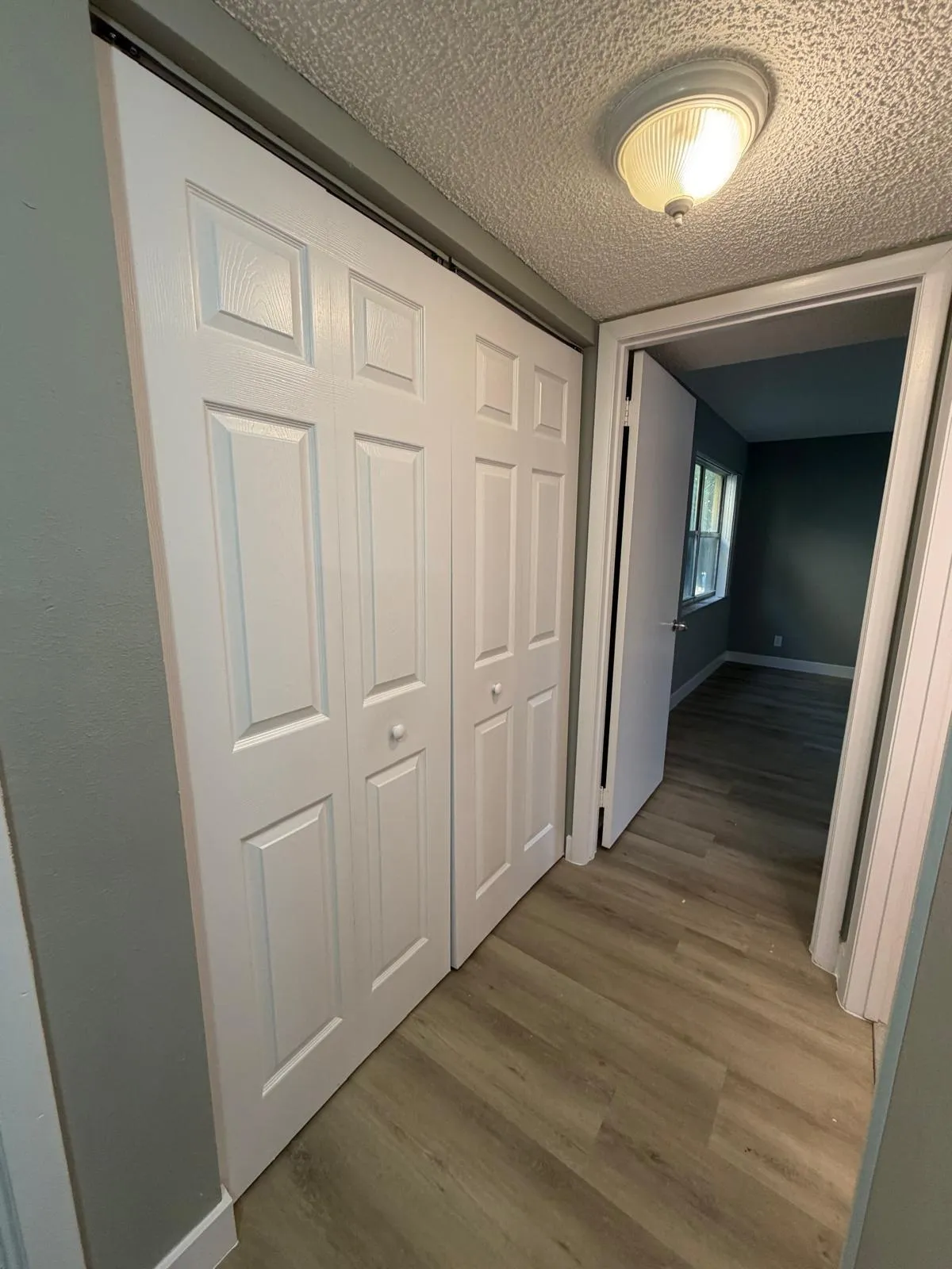 Hallway featuring wood-finish flooring, paneled bifold closet doors, and recessed lighting
