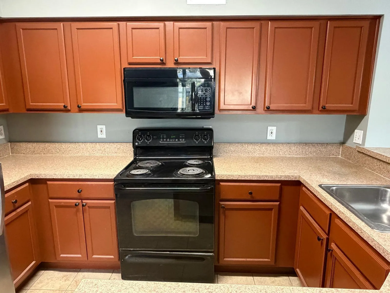 Kitchen featuring extensive cabinetry, laminate countertops, a built-in microwave, an electric range, and a stainless steel sink