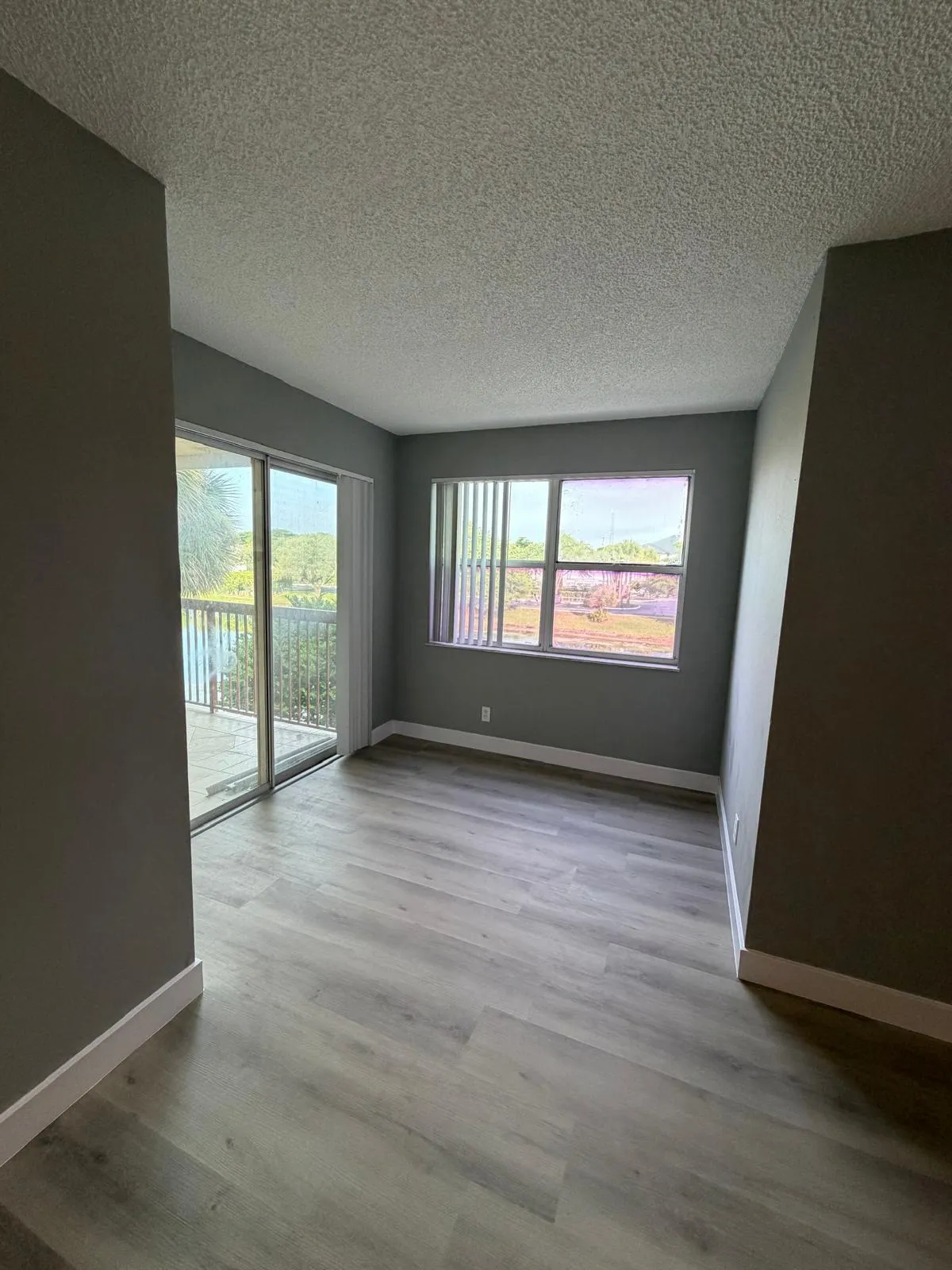 Light wood-finish flooring complemented by a sliding glass door and a window with blinds