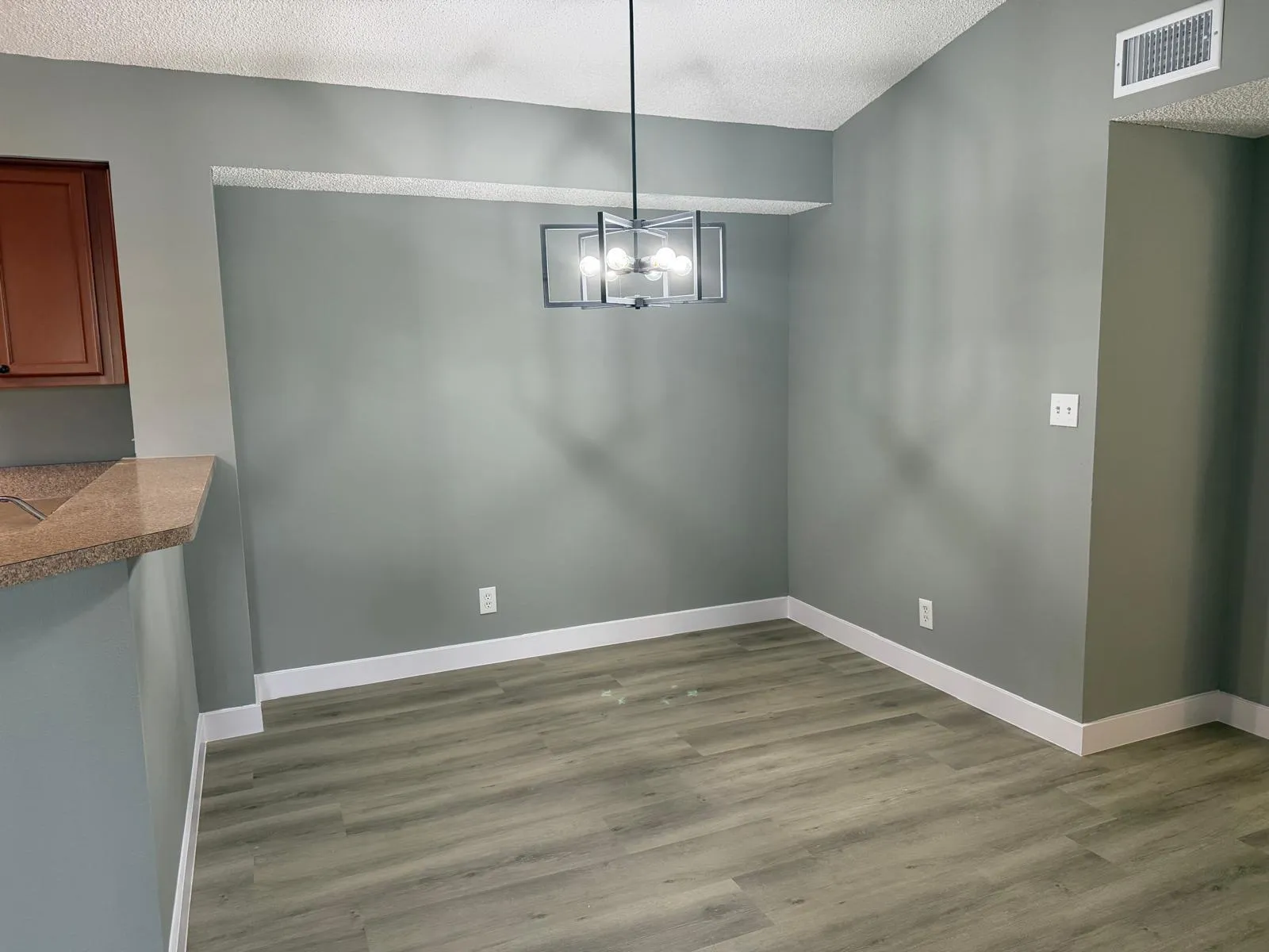 Dining area featuring a modern geometric chandelier, wood-finish flooring, and crisp white baseboards