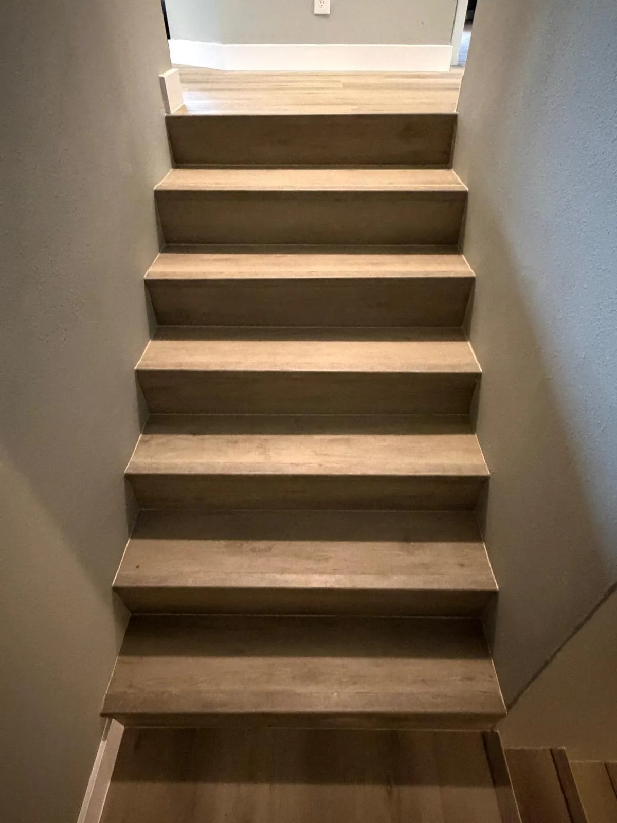 Staircase featuring wood-finish treads and risers, complemented by light gray wall finishes and white baseboard trim
